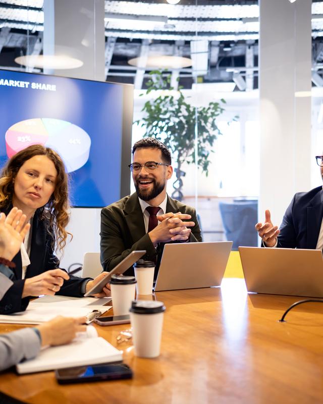 Vier Personen sitzen an einem Tisch in einem modernen Büro und unterhalten sich