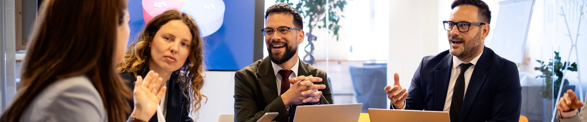 Vier Personen sitzen an einem Tisch in einem modernen Büro und unterhalten sich
