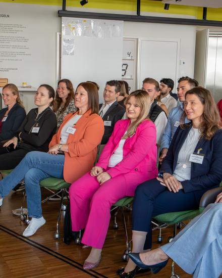 NextGen_MeettheCFO_05_2026 Gruppe von Menschen in Businesskleidung sitzt in einem Raum mit Holzboden