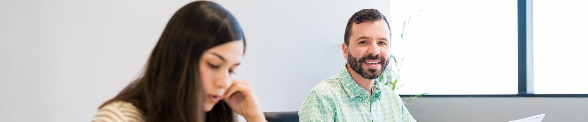 Zwei Personen sitzen an einem Tisch mit Laptops und unterhalten sich Zwei Personen sitzen an einem Tisch mit Laptops und unterhalten sich