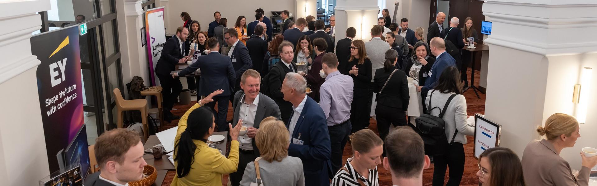 GRC_DAY_2025 Menschen in einem hellen Raum mit gewölbter Decke bei einer Netzwerkveranstaltung, Gespräche und Stehtische sichtbar